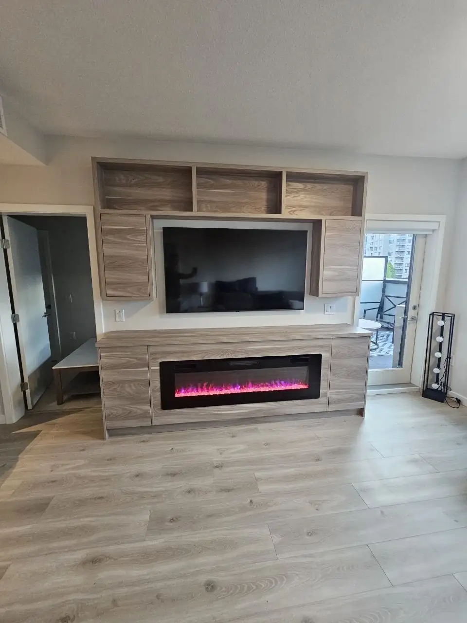 Custom TV wall with open shelving and a built-in electric fireplace