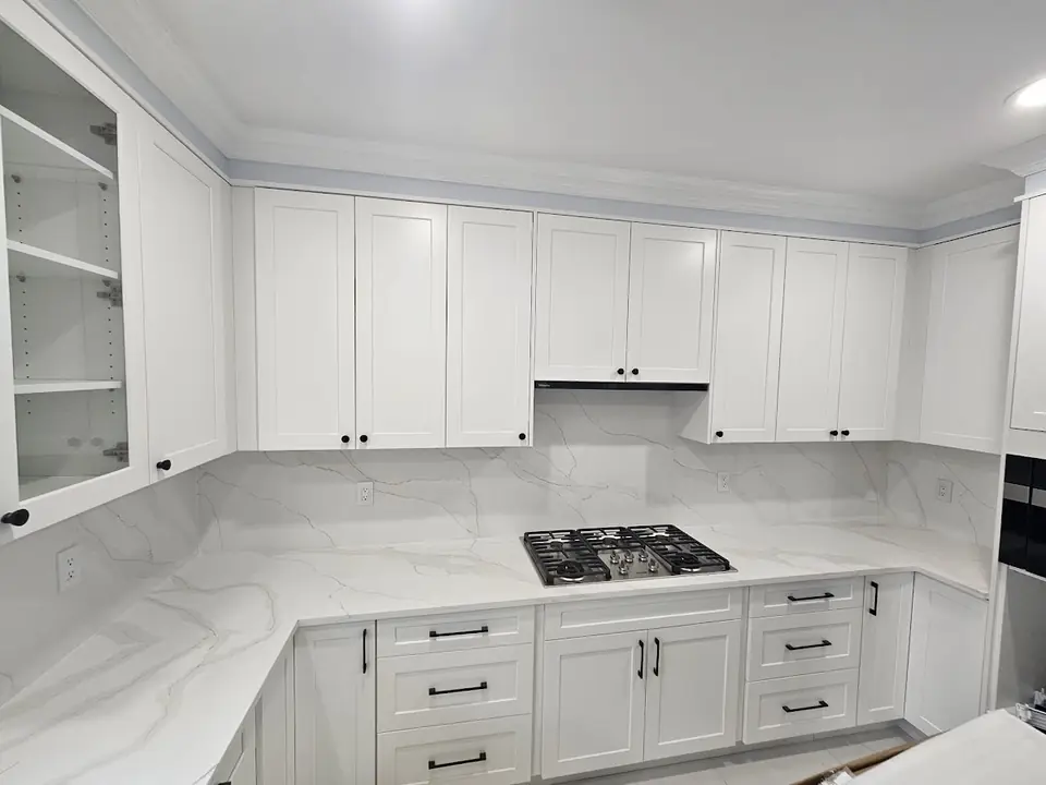 White shaker kitchen cabinets with a marble-look backsplash in Capilano, North Vancouver