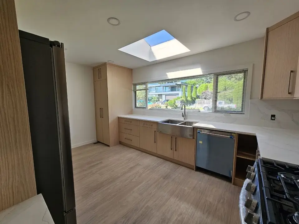 Delbrook kitchen renovation with light wood cabinets, a stainless farmhouse sink and a long window