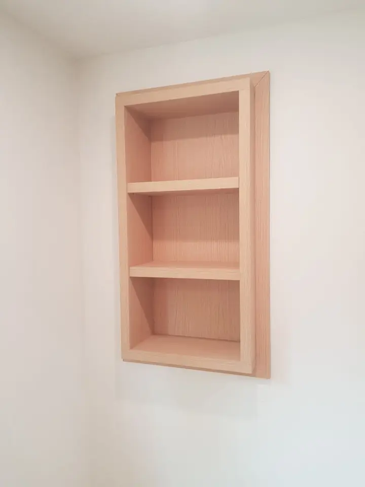 Recessed wall niche with built-in wood shelves in a Delbrook home