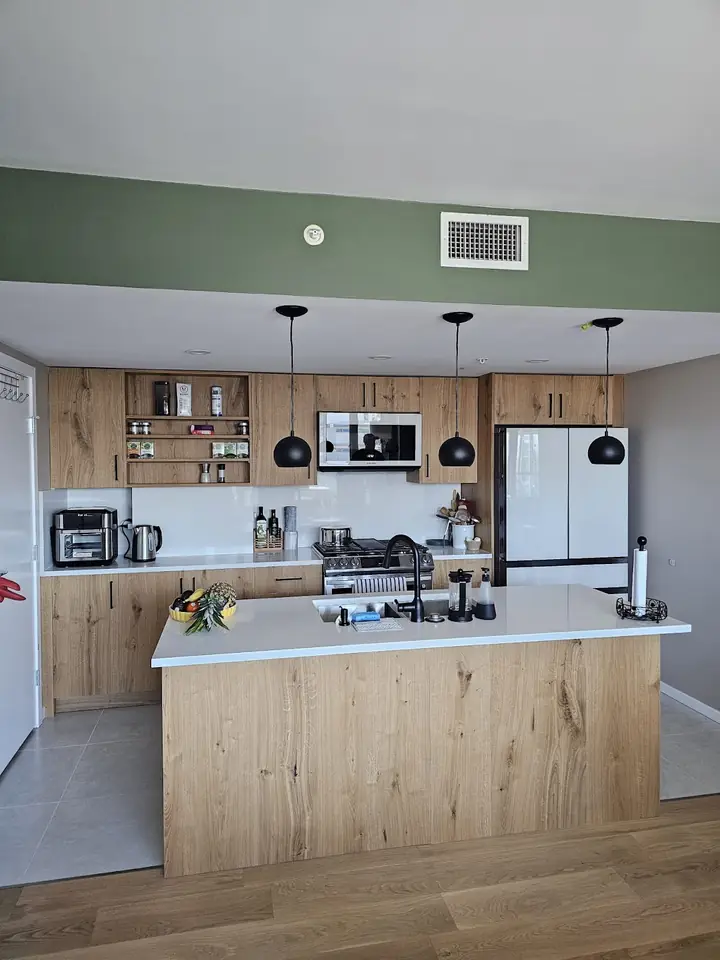 Downtown Vancouver kitchen after renovation with wood cabinets, open shelves, an island and pendant lights