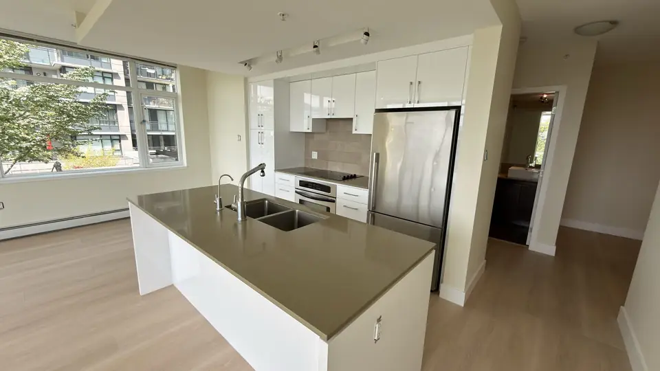 Renovated Lonsdale kitchen with white cabinets, a dark countertop island and a stainless fridge