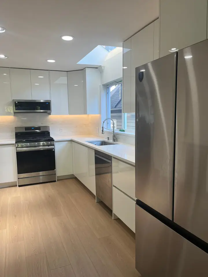 Renovated North Vancouver kitchen with white flat-panel cabinets, stainless appliances and new plank flooring