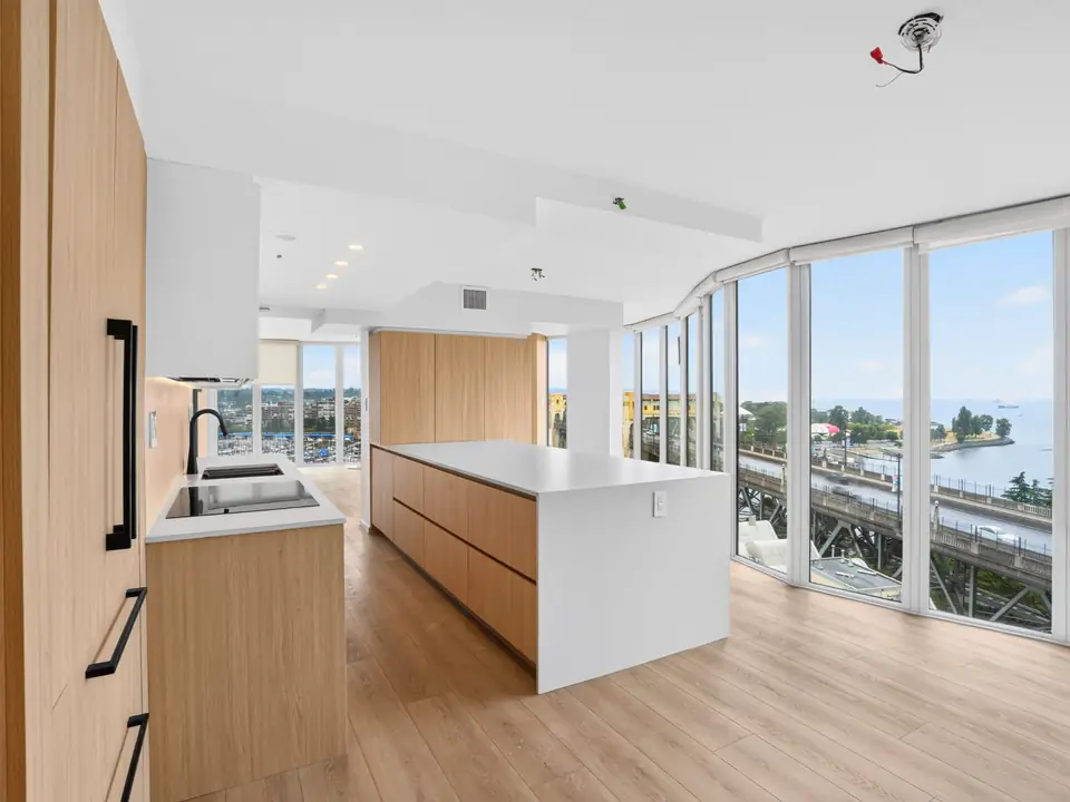 Renovated Yaletown kitchen with light wood cabinetry, a long island and floor-to-ceiling windows